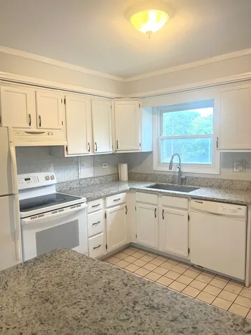 a kitchen with granite countertop white cabinets sink and window