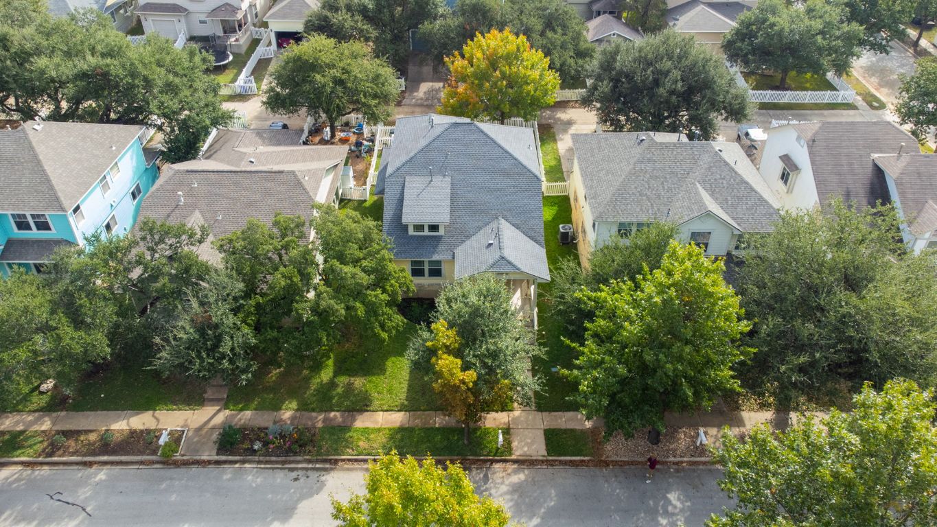 an aerial view of a house with a yard and a large tree