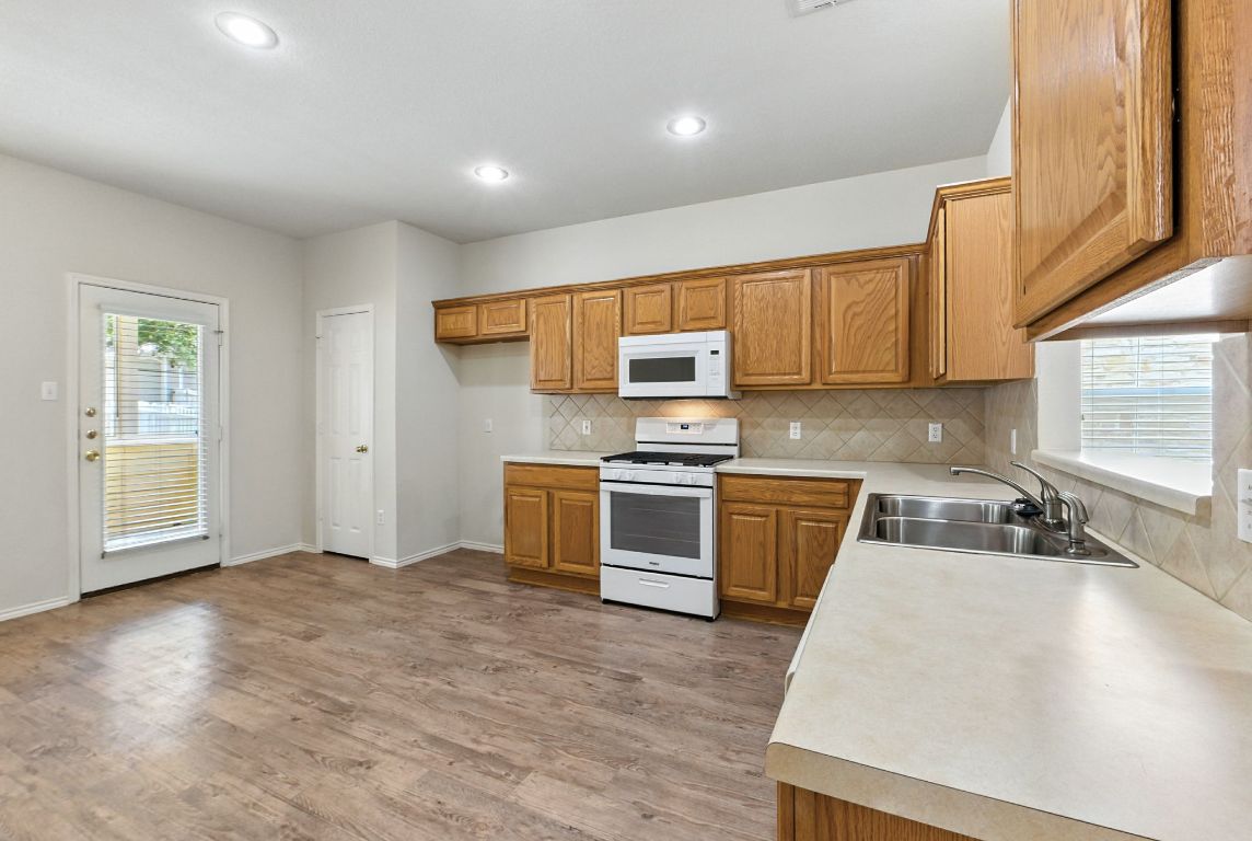 1114 Peyton Place Cedar Park, TX 78613 - Photo 11 of 39 Kitchen with plenty of natural light, white appliances, light countertops, brown cabinets, and recessed lighting