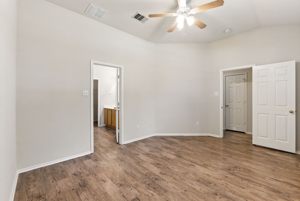 1114 Peyton Place Cedar Park, TX 78613 - Photo 16 of 39 Unfurnished bedroom featuring vaulted ceiling, dark wood-style floors, ensuite bath, and a ceiling fan
