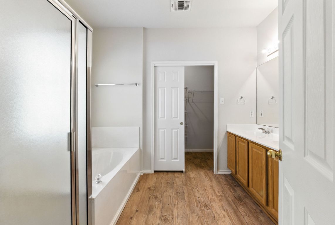 1114 Peyton Place Cedar Park, TX 78613 - Photo 17 of 39 Full bath with a bath, a shower stall, light wood-style floors, and vanity