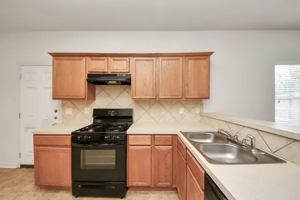 a kitchen with granite countertop a sink stove and cabinets