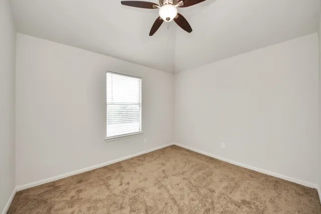 a view of an empty room with a chandelier fan