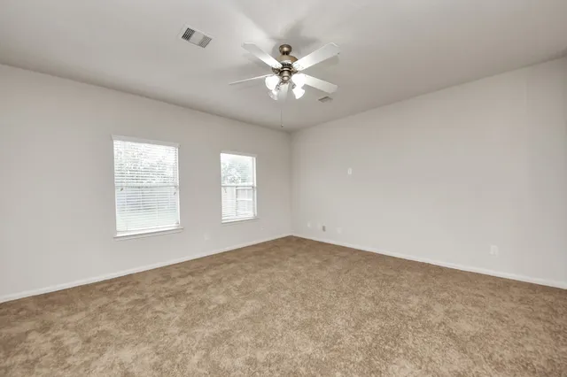 an empty room with windows and ceiling fan
