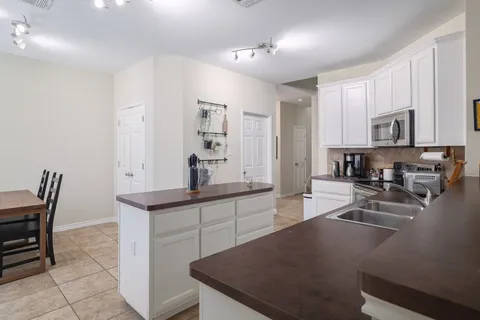 a kitchen with stainless steel appliances granite countertop a sink a stove white cabinets with a dining table and chairs