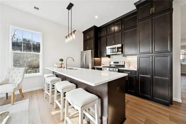 a kitchen with stainless steel appliances granite countertop a sink refrigerator and cabinets