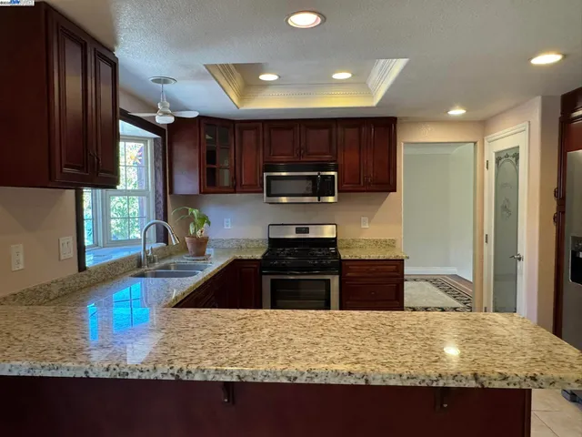 a kitchen with stainless steel appliances granite countertop a sink stove and microwave