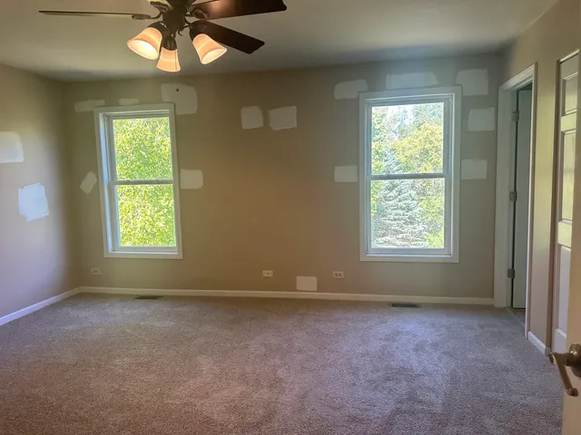 an empty room with windows and chandelier fan