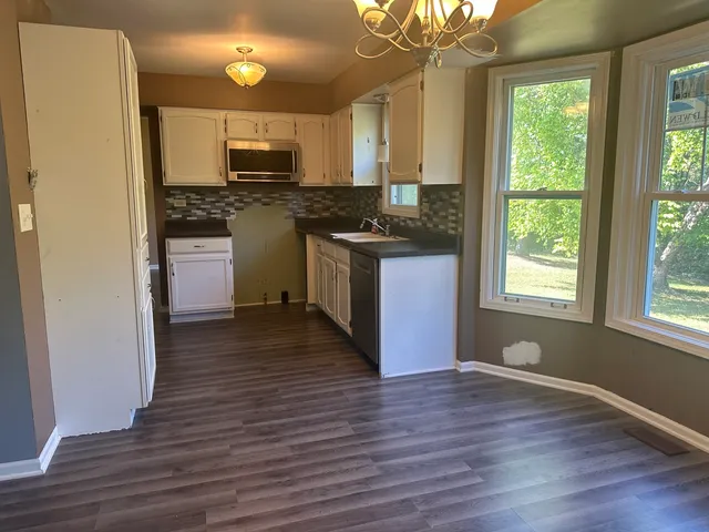 a kitchen with granite countertop wooden floors a sink stainless steel appliances and window