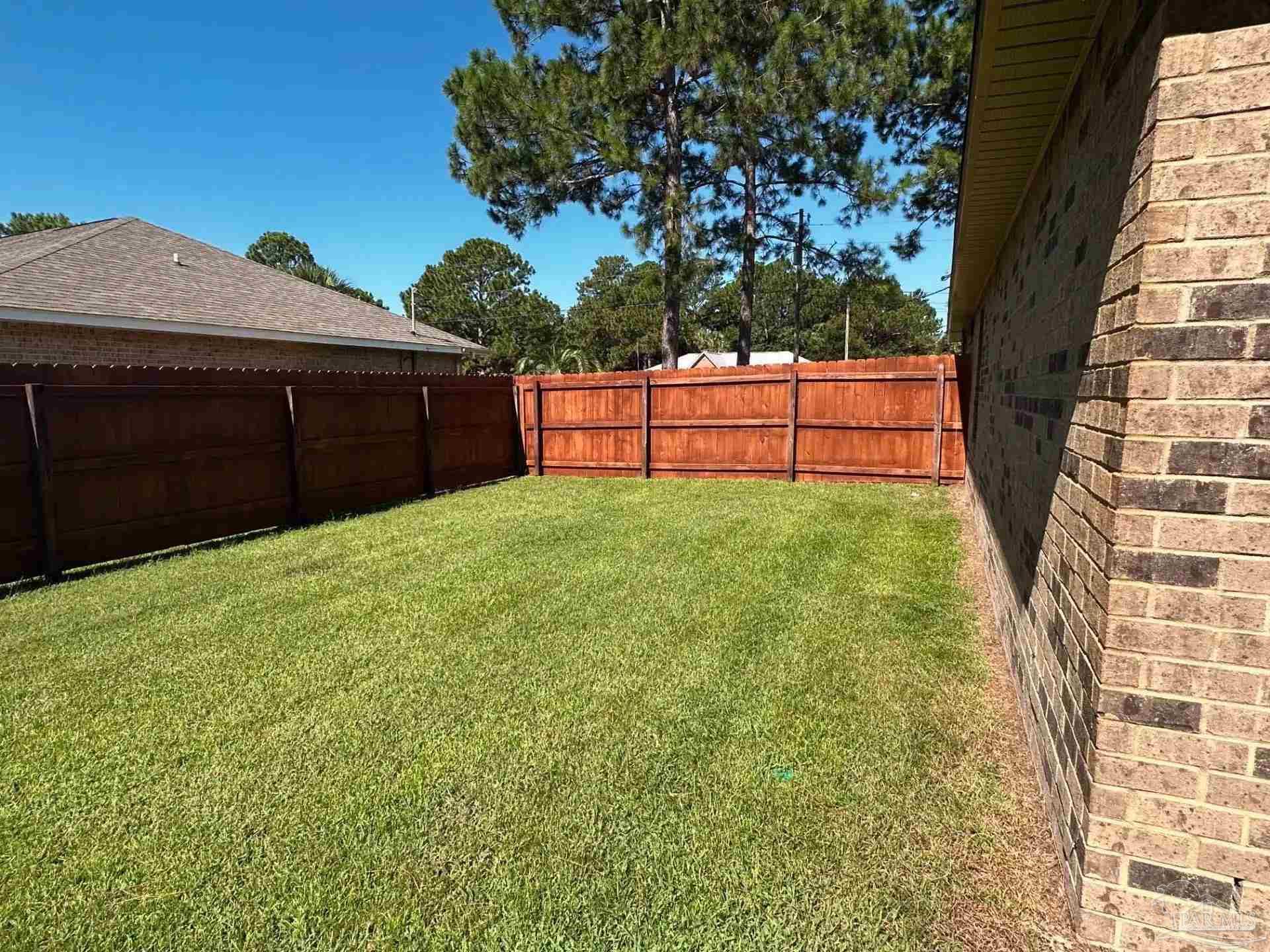 1938 Commodore Drive Navarre, FL 32566 - Photo 20 of 24 a view of backyard with wooden fence and a bench