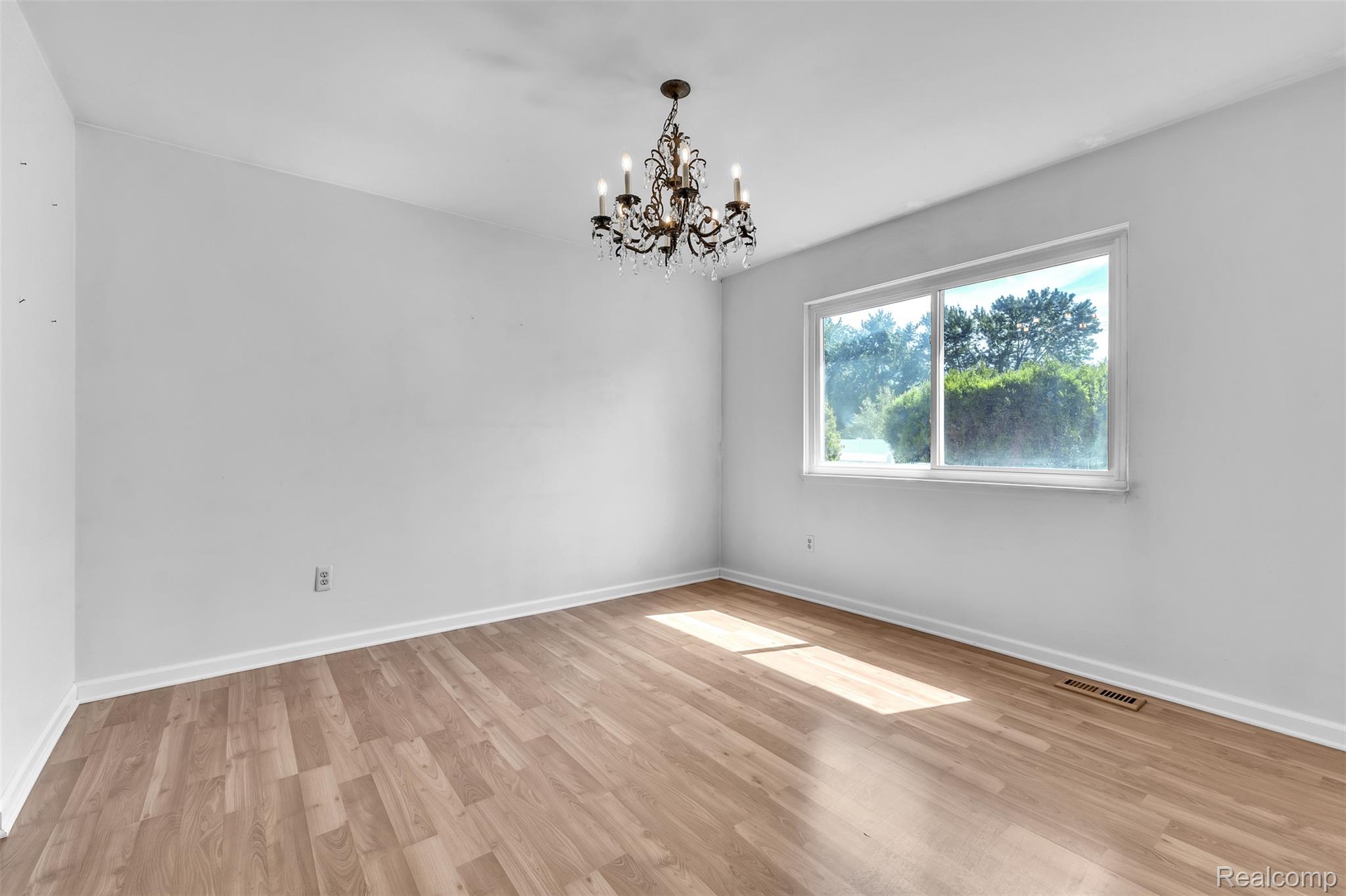 7000 Woonsocket Street Canton, MI 48187 - Photo 13 of 65 Spacious room with wood-finish flooring, a large window, a decorative chandelier, and white baseboards