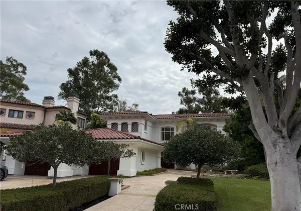 a front view of a house with a garden and tree