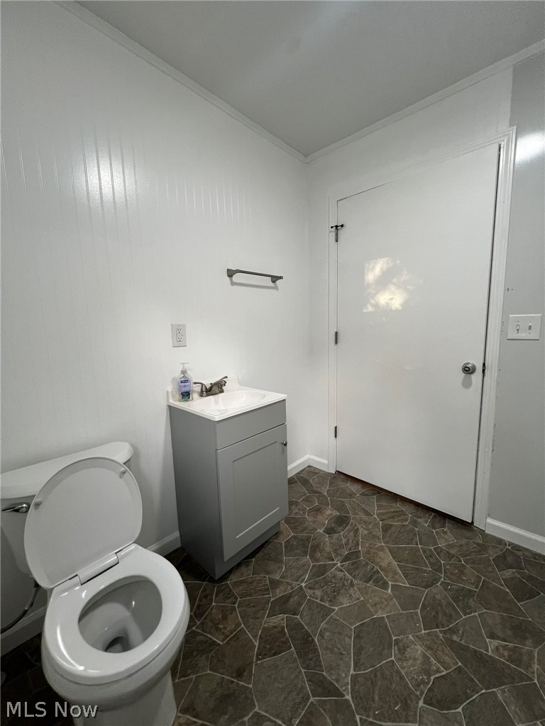 1105 Dutch Ridge Road Guysville, OH 45735 - Photo 15 of 33 Bathroom featuring a white toilet, a gray vanity with a white countertop, and dark flagstone-patterned flooring