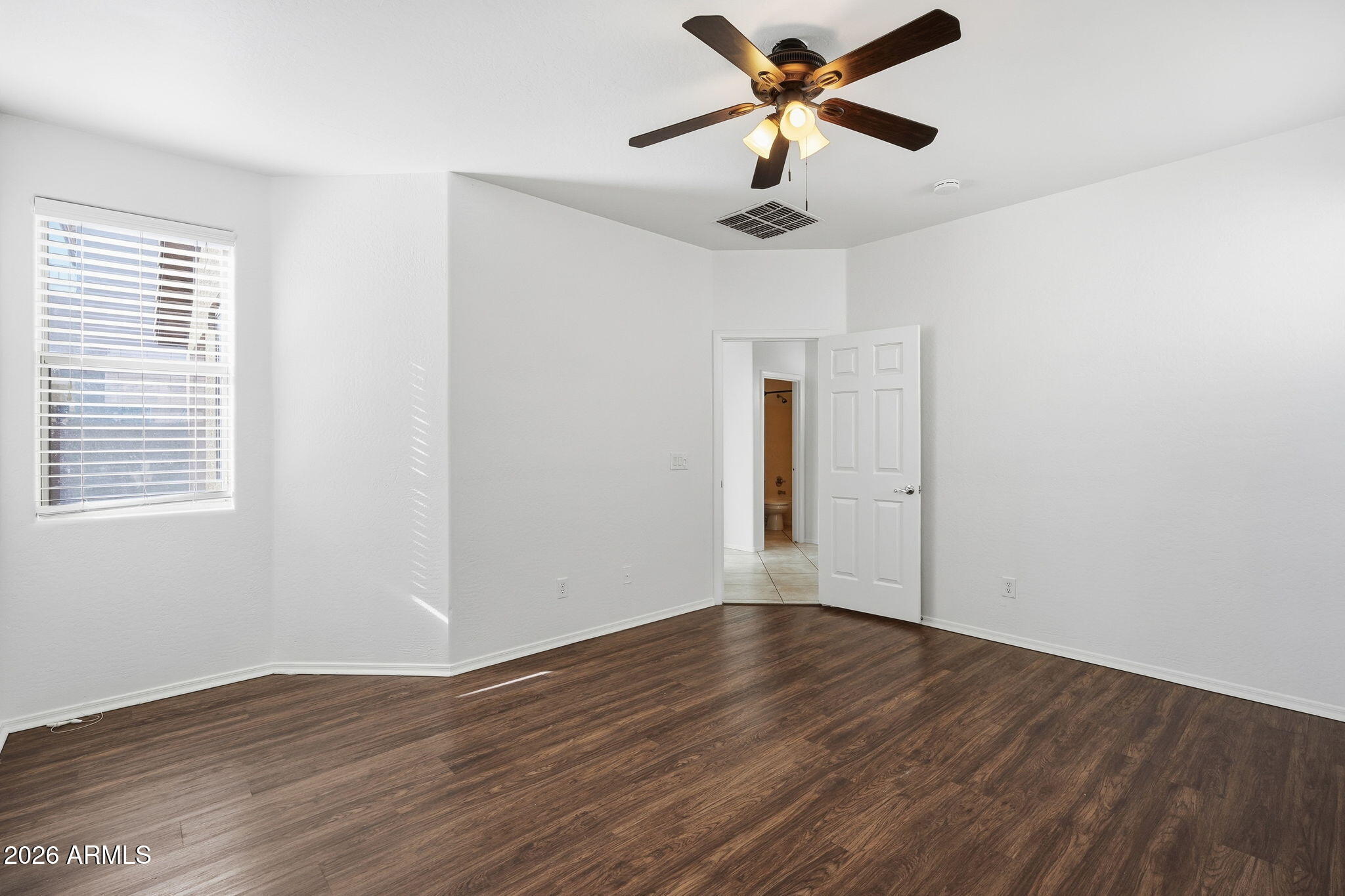 8851 West Payson Road Tolleson, AZ 85353 - Photo 21 of 32 a view of an empty room with wooden floor and a window