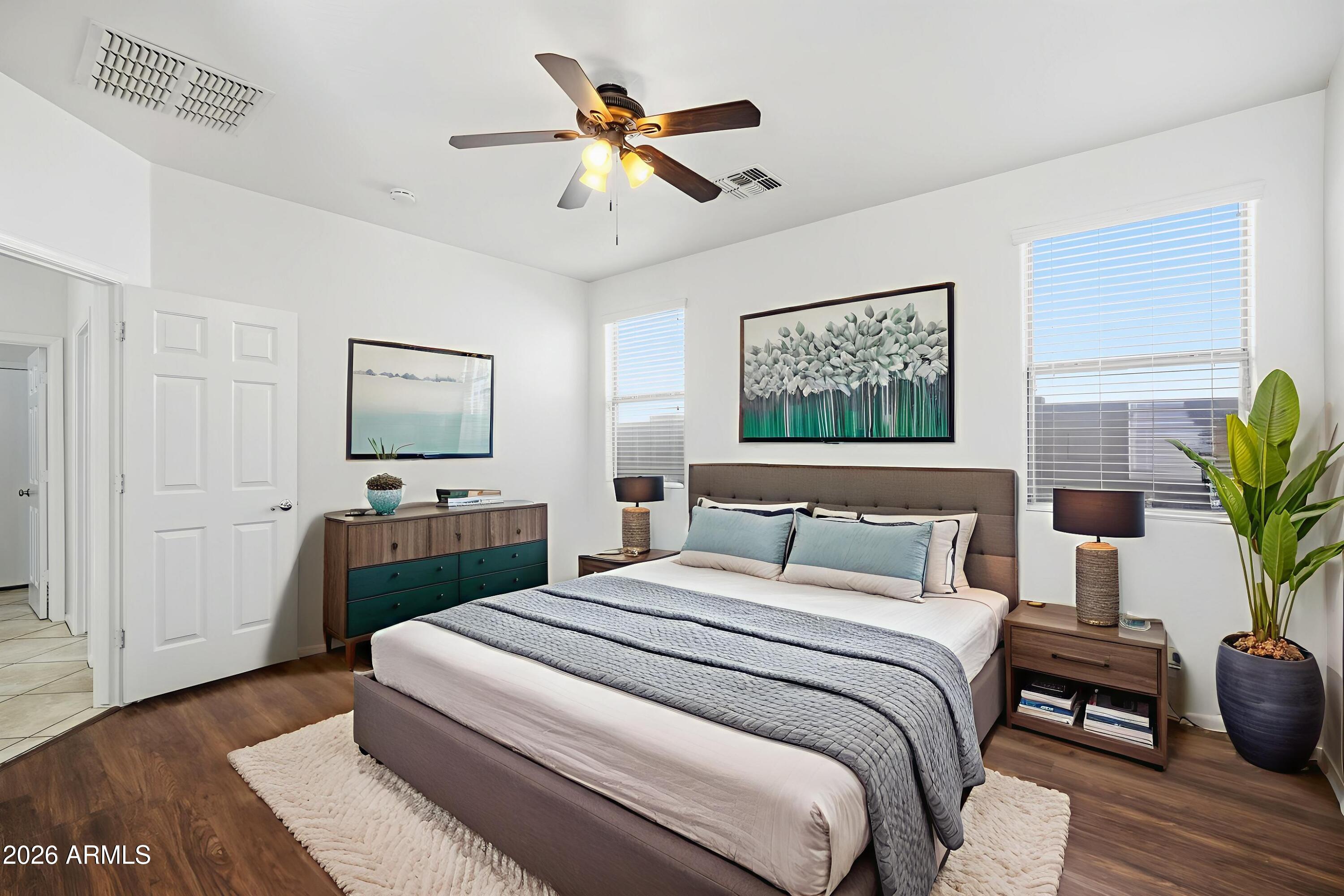 8851 West Payson Road Tolleson, AZ 85353 - Photo 22 of 32 a bedroom with a bed a dresser and potted plants