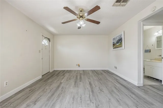 an empty room with wooden floor and ceiling fan