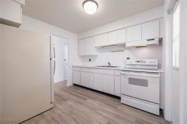 a kitchen with white cabinets and white appliances