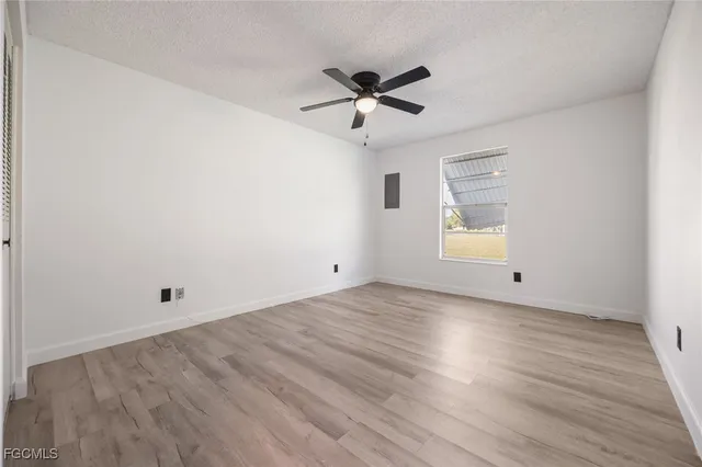 an empty room with wooden floor ceiling fan and windows