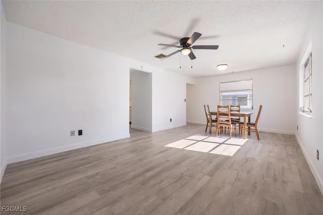 a view of a room with wooden floor ceiling fan and windows