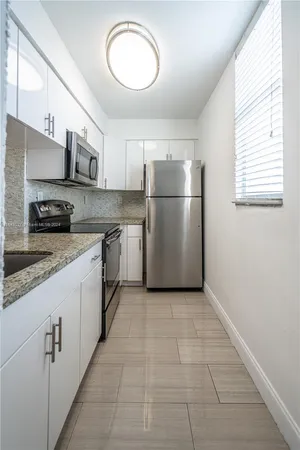 a kitchen with a sink a refrigerator and cabinets