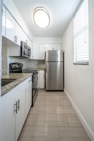 a kitchen with a sink a refrigerator and cabinets