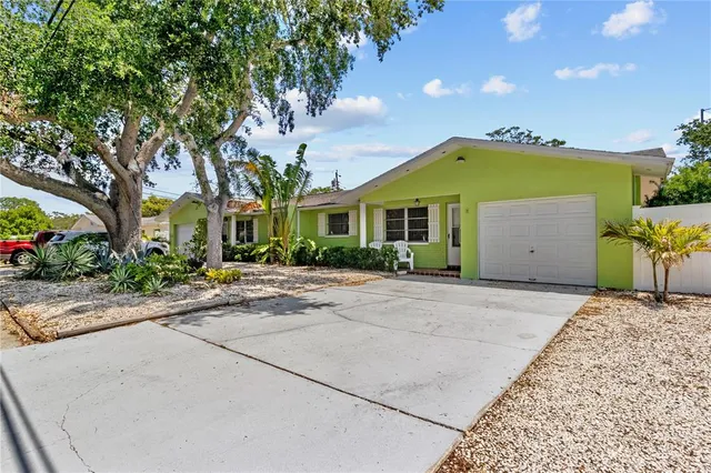 a front view of a house with a garden and trees