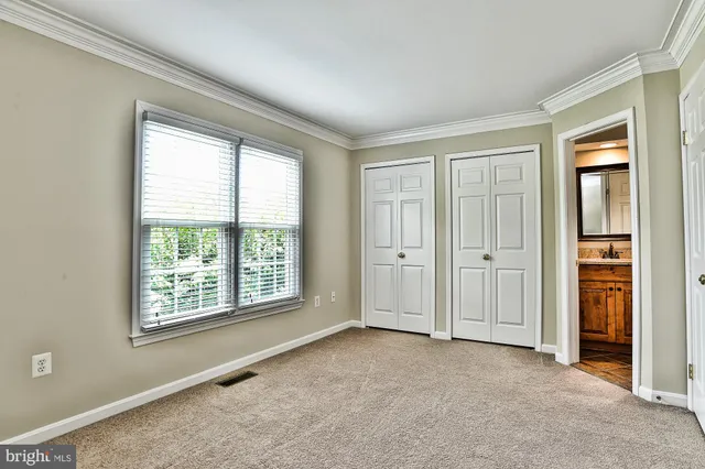 a view of an empty room with closet and a window