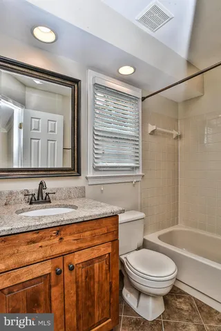 a bathroom with a granite countertop sink toilet mirror and bathtub