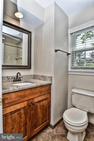 a bathroom with a granite countertop toilet sink and mirror