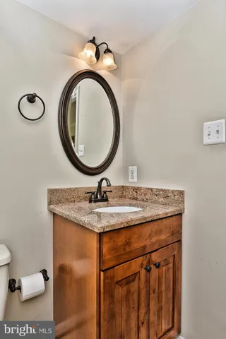 a bathroom with a granite countertop sink a mirror and toilet