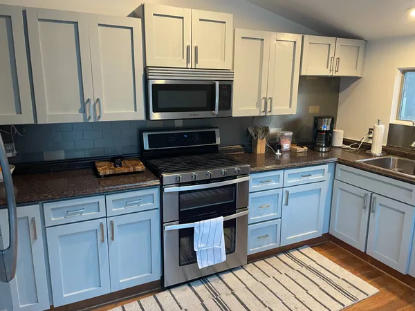 a kitchen with stainless steel appliances granite countertop a stove a sink and a microwave