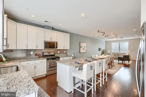 a kitchen with stainless steel appliances granite countertop a stove top oven a sink a stove a dining table and chairs