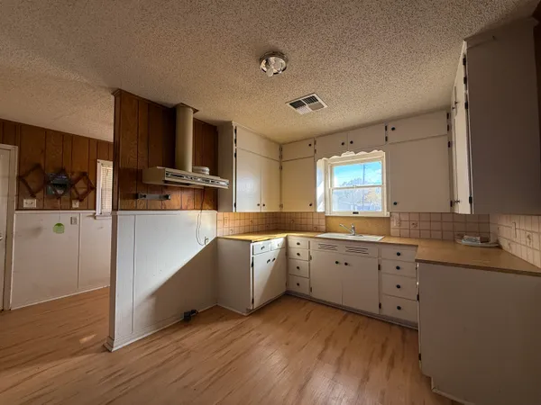 a large kitchen with a lot of counter space and wooden floor