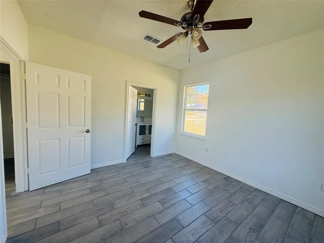 an empty room with wooden floor closet and windows