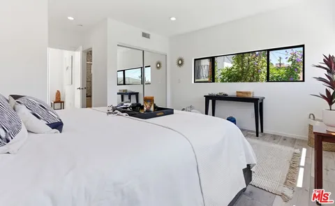 a bedroom with a bed and a flat tv screen on dresser