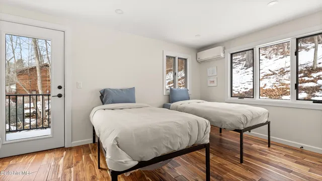 a bedroom with two beds and wooden floor