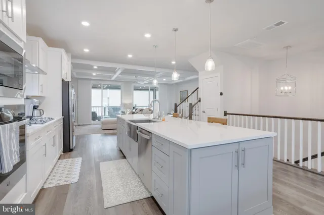 a large white kitchen with a white countertops a stove a dining table and chairs