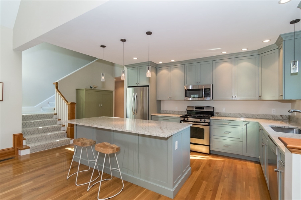 32 Standish Circle Wellesley, MA 02481 - Photo 26 of 41 a kitchen with stainless steel appliances granite countertop a stove top oven a sink dishwasher a dining table and chairs with wooden floor