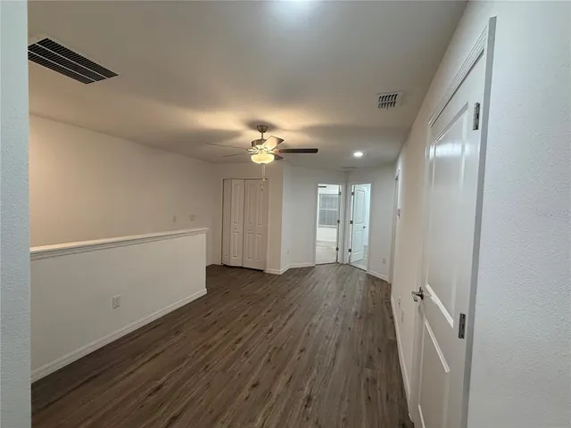 a view of a hallway with wooden floor and chandelier