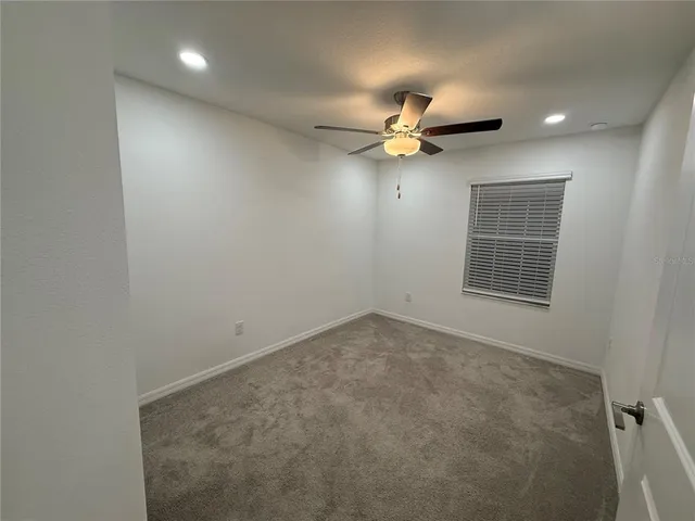 an empty room with a ceiling fan and a window
