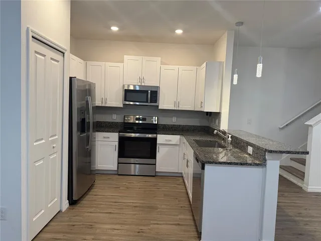 a kitchen with stainless steel appliances granite countertop a refrigerator a stove and a sink