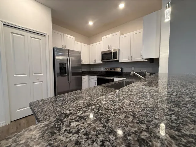 a kitchen with stainless steel appliances granite countertop a refrigerator a stove a sink and a granite counter tops