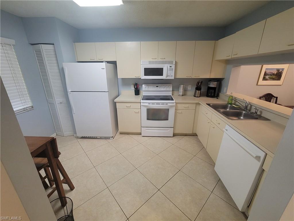 7731 Jewel Lane, Unit 204 Naples, FL 34109 - Photo 11 of 29 a kitchen with a refrigerator sink stove and white cabinets