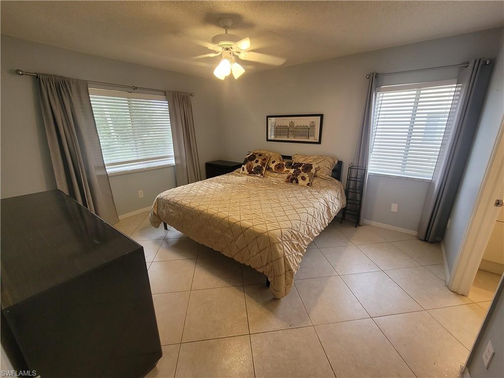 7731 Jewel Lane, Unit 204 Naples, FL 34109 - Photo 14 of 29 a bedroom with a bed and a chandelier