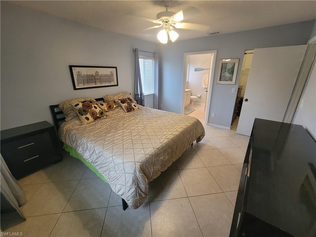 7731 Jewel Lane, Unit 204 Naples, FL 34109 - Photo 15 of 29 a bedroom with a bed and a chandelier