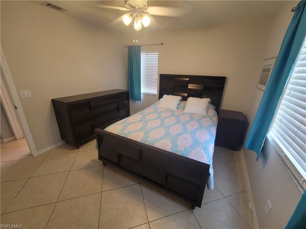 7731 Jewel Lane, Unit 204 Naples, FL 34109 - Photo 18 of 29 a bedroom with a bed and a lamp