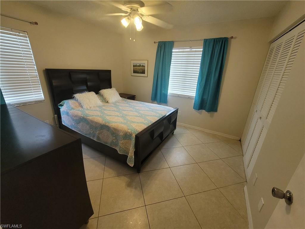 7731 Jewel Lane, Unit 204 Naples, FL 34109 - Photo 19 of 29 a bedroom with a bed and a chandelier