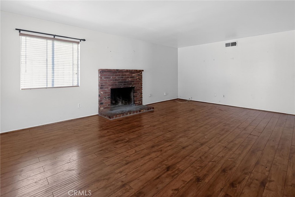 404 South 3rd Street Montebello, CA 90640 - Photo 4 of 29 an empty room with wooden floor fireplace and windows