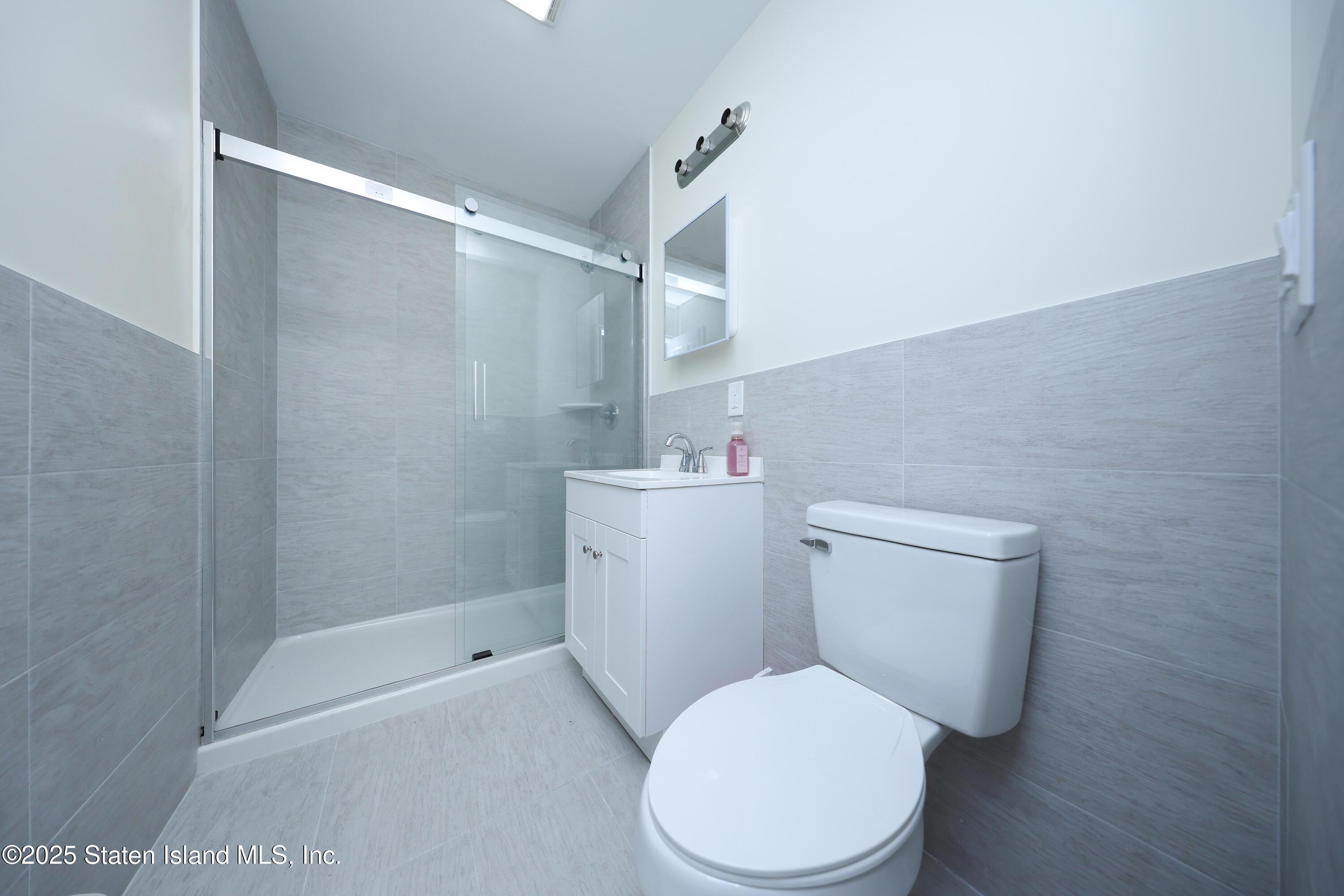 76 Simonson Avenue Staten Island, NY 10303 - Photo 6 of 21 a white toilet sitting next to a bathroom sink and vanity