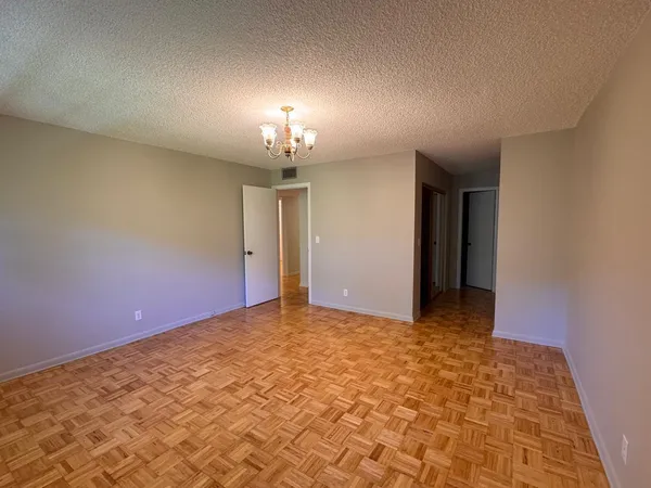an empty room with a chandelier fan and windows